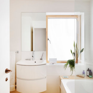 Aménagement d'une petit salle de bain scandinave pour enfant avec un placard à porte plane, des portes de placard blanches, une baignoire posée, un combiné douche/baignoire, un WC suspendu, un carrelage blanc, des carreaux de porcelaine, un mur blanc, un sol en linoléum, un plan vasque, un sol jaune, une cabine de douche à porte battante et un plan de toilette blanc.