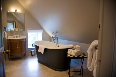 Bild på ett mellanstort lantligt en-suite badrum, med möbel-liknande, skåp i mellenmörkt trä, en kantlös dusch, en toalettstol med hel cisternkåpa, beige kakel, beige väggar, ett konsol handfat och bänkskiva i akrylsten