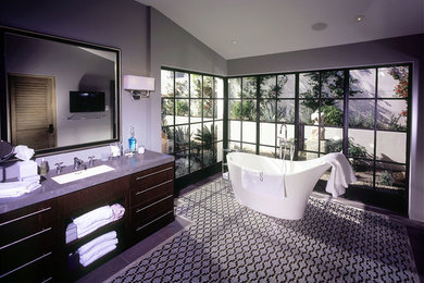 Großes Mediterranes Badezimmer En Suite mit flächenbündigen Schrankfronten, dunklen Holzschränken, freistehender Badewanne, grauer Wandfarbe, Keramikboden, Unterbauwaschbecken, Quarzit-Waschtisch und buntem Boden in Los Angeles