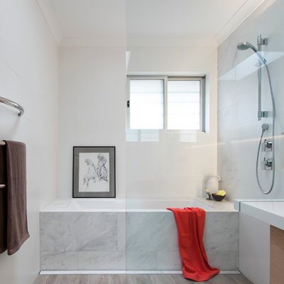 Inspiration for a small contemporary 3/4 white tile and ceramic tile ceramic tile bathroom remodel in Sydney with a wall-mount sink, light wood cabinets, solid surface countertops, an undermount tub, white walls and flat-panel cabinets