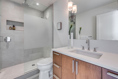 Inspiration for a mid-sized contemporary 3/4 gray tile and porcelain tile porcelain tile and gray floor alcove shower remodel in Vancouver with flat-panel cabinets, medium tone wood cabinets, a one-piece toilet, white walls, an undermount sink, quartz countertops, a hinged shower door and white countertops