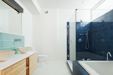 Large contemporary ensuite bathroom in Philadelphia with flat-panel cabinets, light wood cabinets, a built-in bath, a corner shower, a two-piece toilet, black tiles, ceramic tiles, white walls, a vessel sink, engineered stone worktops, white floors and a hinged door.