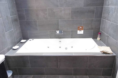 Modelo de cuarto de baño principal contemporáneo de tamaño medio con jacuzzi, baldosas y/o azulejos grises, baldosas y/o azulejos de porcelana, paredes grises y suelo de baldosas de porcelana