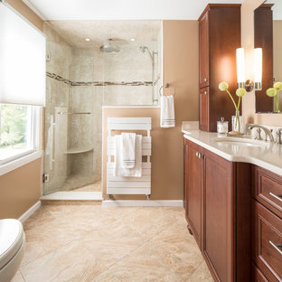 Exempel på ett mellanstort klassiskt en-suite badrum, med luckor med infälld panel, skåp i mellenmörkt trä, en dusch i en alkov, en toalettstol med hel cisternkåpa, beige kakel, beige väggar, ett undermonterad handfat, travertinkakel, travertin golv, bänkskiva i akrylsten, beiget golv och dusch med gångjärnsdörr