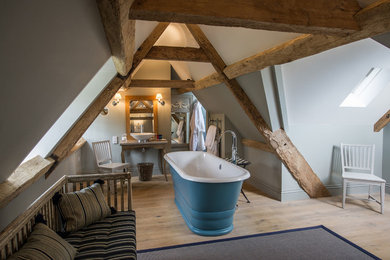 ロンドンにある中くらいなカントリー風のおしゃれな浴室 (置き型浴槽、グレーの壁、淡色無垢フローリング、ベッセル式洗面器、ベージュの床、木製洗面台) の写真