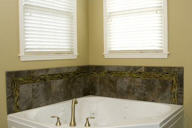 Modelo de cuarto de baño principal clásico renovado de tamaño medio con bañera esquinera, baldosas y/o azulejos grises, suelo de baldosas de porcelana, lavabo bajoencimera, encimera de granito, suelo gris, ducha con puerta con bisagras y encimeras multicolor