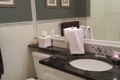 インディアナポリスにある中くらいなトラディショナルスタイルのおしゃれなマスターバスルーム (インセット扉のキャビネット、白いキャビネット、白いタイル、大理石の洗面台、ガラスタイル、アルコーブ型浴槽、シャワー付き浴槽	、グレーの壁、セラミックタイルの床、アンダーカウンター洗面器、分離型トイレ、白い床、シャワーカーテン) の写真