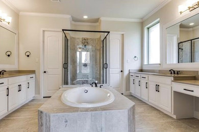 Photo of a large traditional ensuite bathroom in Dallas with raised-panel cabinets, white cabinets, a built-in bath, an alcove shower, brown tiles, porcelain tiles, beige walls, porcelain flooring, a submerged sink, engineered stone worktops and beige floors.