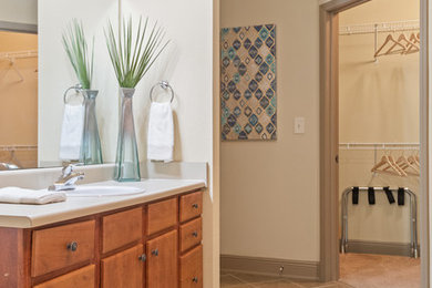Aménagement d'une salle de bain classique en bois brun avec un placard à porte plane, un carrelage beige, un mur beige, un lavabo posé et un sol beige.