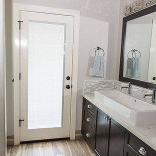 Bild på ett stort vintage en-suite badrum, med luckor med infälld panel, skåp i mörkt trä, grå kakel, vit kakel, stickkakel, vita väggar, plywoodgolv, ett avlångt handfat, bänkskiva i kvartsit och en dusch i en alkov