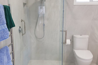 Modern inredning av ett mellanstort en-suite badrum, med ett fristående badkar, en hörndusch, en toalettstol med hel cisternkåpa, grå kakel, keramikplattor, grå väggar, klinkergolv i keramik, grått golv och dusch med skjutdörr