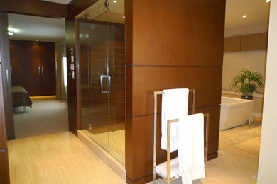 Foto de cuarto de baño principal contemporáneo de tamaño medio con armarios con paneles lisos, puertas de armario de madera oscura, ducha esquinera, bañera exenta, paredes marrones y suelo de madera clara