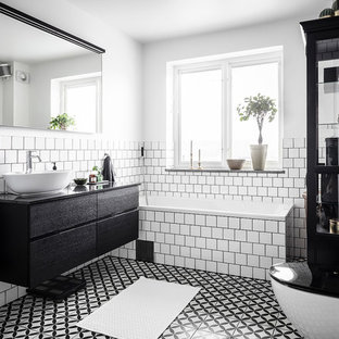 Inredning av ett skandinaviskt stort svart svart en-suite badrum, med en öppen dusch, en vägghängd toalettstol, vit kakel, keramikplattor, vita väggar, cementgolv, granitbänkskiva, flerfärgat golv, med dusch som är öppen, släta luckor, svarta skåp, ett hörnbadkar och ett fristående handfat
