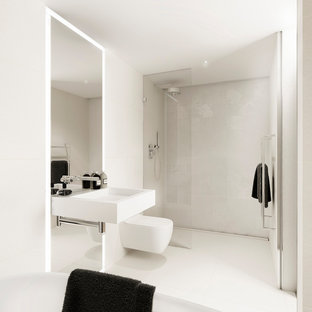 This is an example of a large modern family bathroom in London with a freestanding bath, a wall mounted toilet, beige tiles, white tiles, beige walls, ceramic flooring, a wall-mounted sink, an open shower, a built-in shower and white floors.
