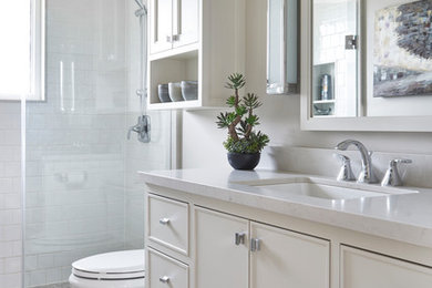 Alcove shower - mid-sized traditional white tile and ceramic tile ceramic tile and beige floor alcove shower idea in Toronto with beige cabinets, a two-piece toilet, beige walls, an undermount sink, quartz countertops, a hinged shower door and recessed-panel cabinets