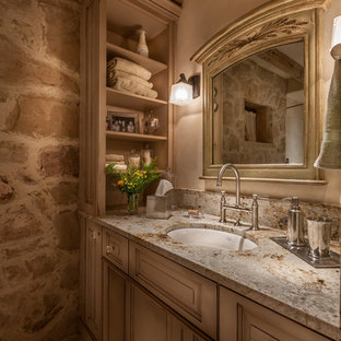 Diseño de cuarto de baño con ducha, clásico, de tamaño medio, con armarios con paneles con relieve, lavabo bajoencimera, puertas de armario con efecto envejecido, baldosas y/o azulejos beige, paredes beige, suelo de baldosas de porcelana y encimera de granito