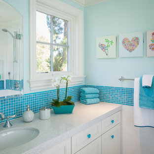 Esempio di una stanza da bagno per bambini tradizionale con lavabo sottopiano, ante a filo, top in vetro riciclato, piastrelle blu, piastrelle in ceramica, pareti blu e pavimento in gres porcellanato