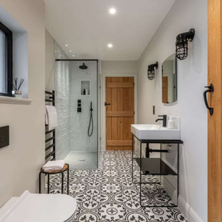 Photo of a large contemporary ensuite bathroom in Buckinghamshire with a wall mounted toilet, beige walls, a console sink, multi-coloured floors, an open shower, a corner shower, a wall niche and a single sink.