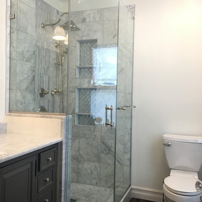 Inspiration for a mid-sized timeless master gray tile, white tile and porcelain tile dark wood floor alcove shower remodel in Newark with recessed-panel cabinets, gray cabinets, a one-piece toilet, white walls and marble countertops