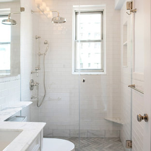 Klassisk inredning av ett litet en-suite badrum, med luckor med upphöjd panel, vita skåp, en dusch i en alkov, en toalettstol med hel cisternkåpa, vit kakel, stenkakel, vita väggar, marmorgolv, ett nedsänkt handfat och bänkskiva i kvartsit
