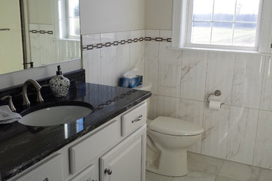 Inspiration for a mid-sized timeless 3/4 gray tile and white tile bathroom remodel in Bridgeport with raised-panel cabinets, white cabinets, a two-piece toilet, beige walls, an undermount sink and granite countertops