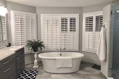 Inspiration for a large timeless master white tile and subway tile gray floor bathroom remodel in St Louis with recessed-panel cabinets, gray cabinets, a two-piece toilet, gray walls, an undermount sink, a hinged shower door, gray countertops, a niche and a built-in vanity