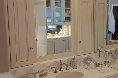 Example of a mid-sized classic master beige tile and marble tile marble floor and beige floor bathroom design in Houston with raised-panel cabinets, beige cabinets, a one-piece toilet, beige walls, a drop-in sink, marble countertops and a hinged shower door