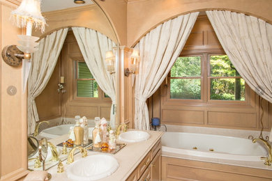 Example of a mid-sized ornate master beige tile and ceramic tile alcove bathtub design in New York with recessed-panel cabinets, light wood cabinets, beige walls, a drop-in sink and limestone countertops