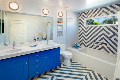 Immagine di una stanza da bagno bohémian con ante in stile shaker, ante blu, vasca sottopiano, vasca/doccia, WC monopezzo, piastrelle blu, piastrelle bianche, pareti bianche, lavabo sottopiano e doccia con tenda