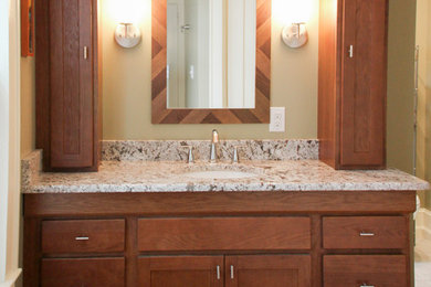 Example of a small classic master medium tone wood floor bathroom design in Charlotte with shaker cabinets, medium tone wood cabinets, a one-piece toilet, green walls, an undermount sink, granite countertops and white countertops