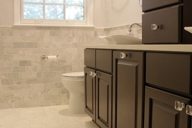 Inspiration for a large transitional master gray tile and marble tile marble floor and white floor bathroom remodel in Atlanta with raised-panel cabinets, dark wood cabinets, marble countertops, a one-piece toilet, a vessel sink, a hinged shower door and gray walls