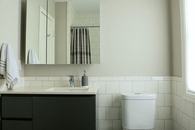 オマハにある中くらいなトランジショナルスタイルのおしゃれなバスルーム (浴槽なし) (フラットパネル扉のキャビネット、グレーのキャビネット、アルコーブ型浴槽、シャワー付き浴槽	、分離型トイレ、白いタイル、磁器タイル、グレーの壁、セメントタイルの床、アンダーカウンター洗面器、クオーツストーンの洗面台、マルチカラーの床、シャワーカーテン) の写真