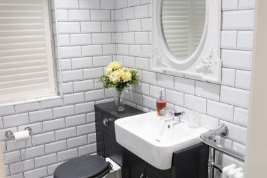 This is an example of a medium sized traditional ensuite bathroom in Hampshire with shaker cabinets, grey cabinets, a walk-in shower, a one-piece toilet, white tiles, ceramic tiles, white walls, vinyl flooring, a built-in sink, wooden worktops, grey floors, an open shower and grey worktops.