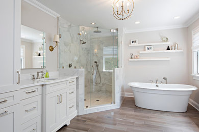 Example of a large transitional master gray tile and marble tile porcelain tile and brown floor bathroom design in New York with shaker cabinets, white cabinets, gray walls, an undermount sink, marble countertops, a hinged shower door and white countertops