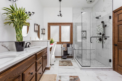 Large trendy master white tile and porcelain tile porcelain tile and white floor corner shower photo in Indianapolis with raised-panel cabinets, medium tone wood cabinets, white walls, an undermount sink, quartzite countertops, a hinged shower door and white countertops