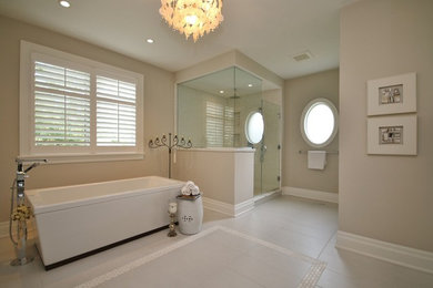 オタワにある中くらいなトランジショナルスタイルのおしゃれなマスターバスルーム (白いキャビネット、大理石の洗面台、置き型浴槽、グレーのタイル、ベージュの壁) の写真