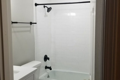 This is an example of a small traditional family bathroom in Birmingham with flat-panel cabinets, white cabinets, a built-in bath, a shower/bath combination, a two-piece toilet, white tiles, metro tiles, grey walls, a submerged sink, engineered stone worktops, a shower curtain and white worktops.
