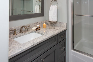 Inspiration for a small transitional kids' vinyl floor and gray floor bathroom remodel in Boston with recessed-panel cabinets, gray cabinets, a two-piece toilet, gray walls, an undermount sink, granite countertops and multicolored countertops