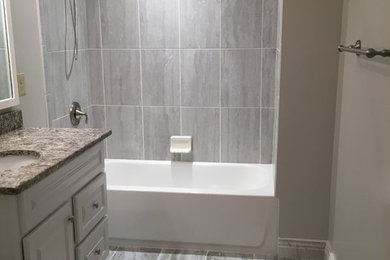 This is an example of a small traditional bathroom in Nashville with raised-panel cabinets, white cabinets, an alcove bath, a shower/bath combination, grey tiles, porcelain tiles, a submerged sink, granite worktops, grey floors, a shower curtain and grey worktops.