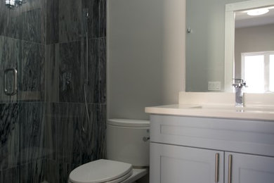 Double shower - small transitional 3/4 ceramic tile and gray floor double shower idea in Miami with gray cabinets, a two-piece toilet, gray walls, an undermount sink, quartzite countertops, a hinged shower door and shaker cabinets