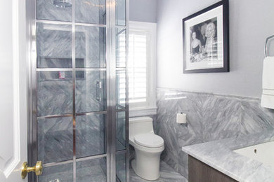 Inspiration for a mid-sized transitional 3/4 gray tile and marble tile marble floor and gray floor corner shower remodel in New York with flat-panel cabinets, dark wood cabinets, a one-piece toilet, gray walls, an undermount sink, marble countertops and a hinged shower door