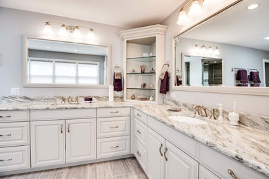 Large traditional ensuite bathroom in Chicago with raised-panel cabinets, white cabinets, a freestanding bath, a corner shower, brown tiles, beige tiles, beige walls, porcelain flooring, a submerged sink, granite worktops, beige floors, a hinged door, beige worktops and porcelain tiles.