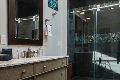 This is an example of a medium sized classic ensuite bathroom in Kansas City with grey walls, dark hardwood flooring, brown floors, flat-panel cabinets, brown cabinets, a freestanding bath, an alcove shower, a submerged sink, marble worktops, a sliding door and white worktops.