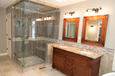 Example of a large transitional master beige tile and ceramic tile ceramic tile and beige floor bathroom design in Calgary with granite countertops, gray walls, an undermount sink, recessed-panel cabinets, medium tone wood cabinets and a hinged shower door