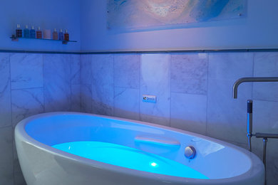 ニューヨークにある中くらいなトランジショナルスタイルのおしゃれなマスターバスルーム (置き型浴槽、白いタイル、青い壁、石タイル、大理石の床) の写真