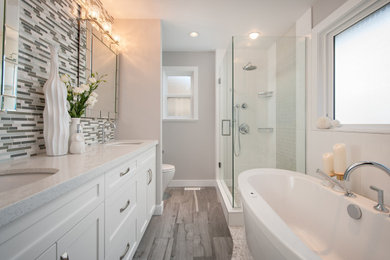 Bathroom - small transitional master gray tile and porcelain tile porcelain tile and gray floor bathroom idea in Vancouver with shaker cabinets, white cabinets, a two-piece toilet, gray walls, an undermount sink, quartz countertops, a hinged shower door and white countertops