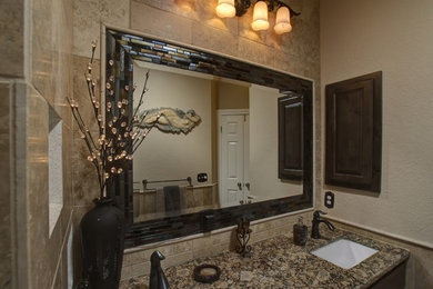 Foto de cuarto de baño tradicional con lavabo bajoencimera, armarios con paneles lisos, puertas de armario de madera en tonos medios, encimera de granito, ducha empotrada y baldosas y/o azulejos de piedra