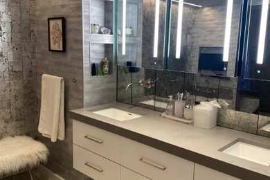 Example of a large trendy master gray tile and glass tile double-sink, porcelain tile, beige floor and wallpaper bathroom design in New York with flat-panel cabinets, white cabinets, concrete countertops, gray countertops, a floating vanity, an undermount sink, a one-piece toilet, white walls and a hinged shower door