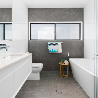 Design ideas for a contemporary bathroom in Sydney with flat-panel cabinets, white cabinets, a freestanding tub, a corner shower, gray tile, white tile, white walls, an undermount sink, grey floor, a hinged shower door and beige benchtops.