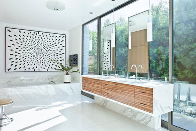 Trendy bathroom photo in Los Angeles with flat-panel cabinets, dark wood cabinets, an undermount tub and white walls